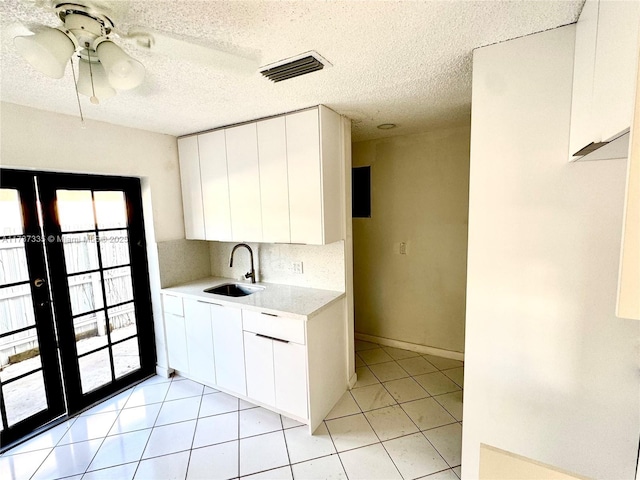 kitchen featuring french doors, sink, tasteful backsplash, and white cabinets