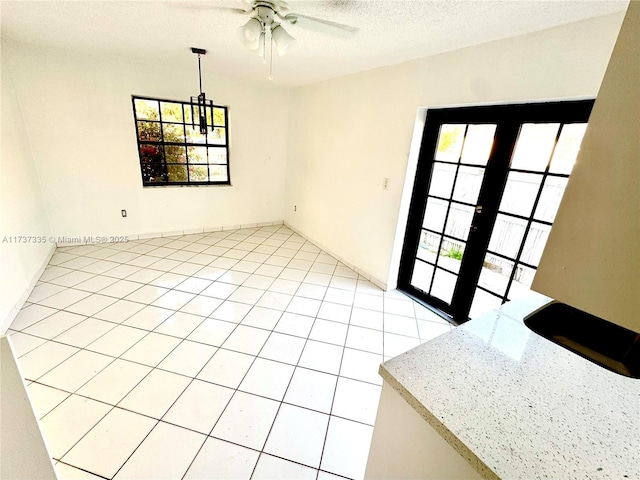 empty room featuring ceiling fan, a textured ceiling, french doors, and a healthy amount of sunlight