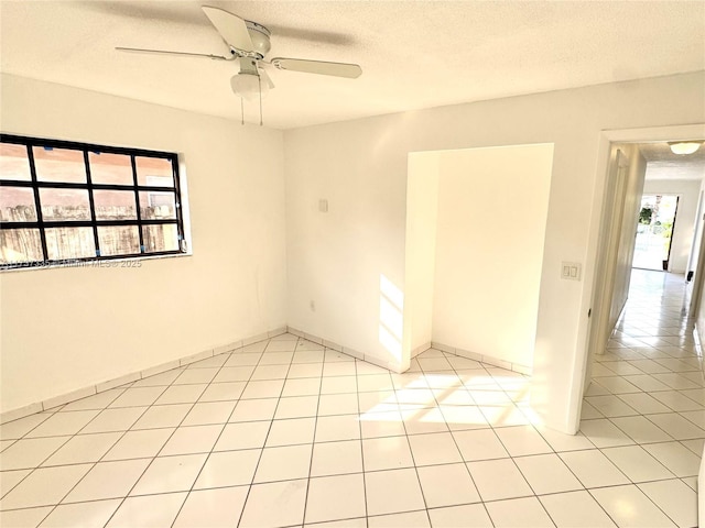 tiled empty room with ceiling fan and a textured ceiling