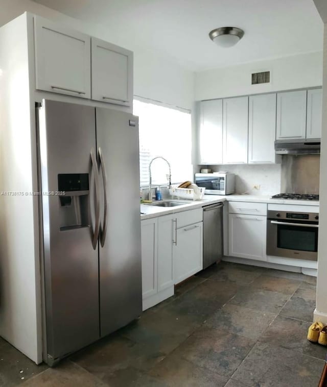 kitchen with tasteful backsplash, stainless steel appliances, sink, and white cabinets