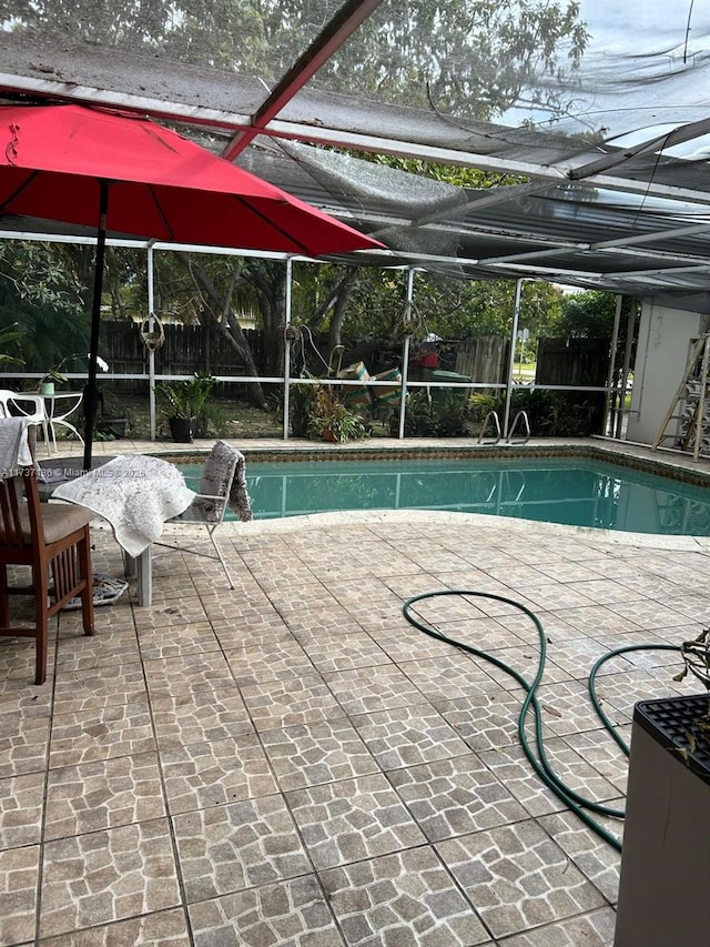 view of pool with glass enclosure and a patio area