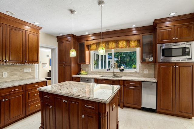 kitchen featuring sink, decorative light fixtures, a center island, stainless steel appliances, and light stone countertops