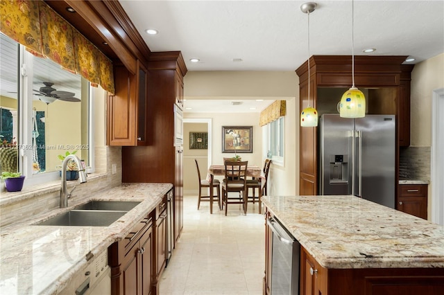 kitchen featuring sink, light stone counters, high end refrigerator, hanging light fixtures, and backsplash