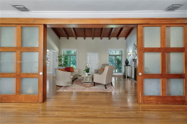 living area with wood ceiling, beam ceiling, a healthy amount of sunlight, and hardwood / wood-style flooring