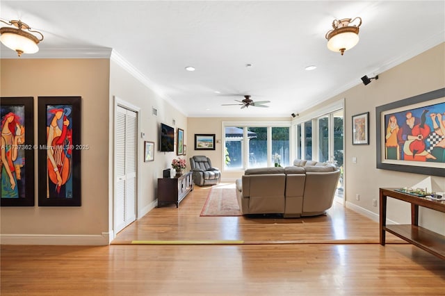 living room with ornamental molding, ceiling fan, and light wood-type flooring