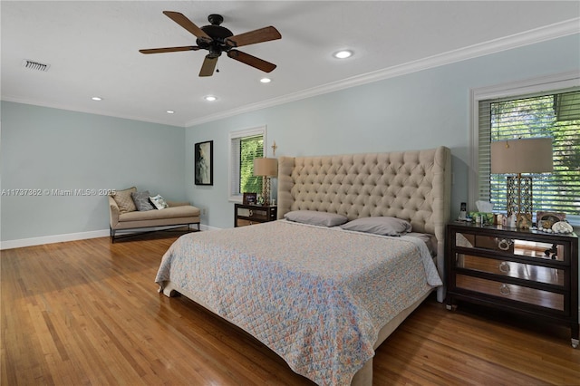 bedroom with multiple windows, wood-type flooring, ornamental molding, and ceiling fan