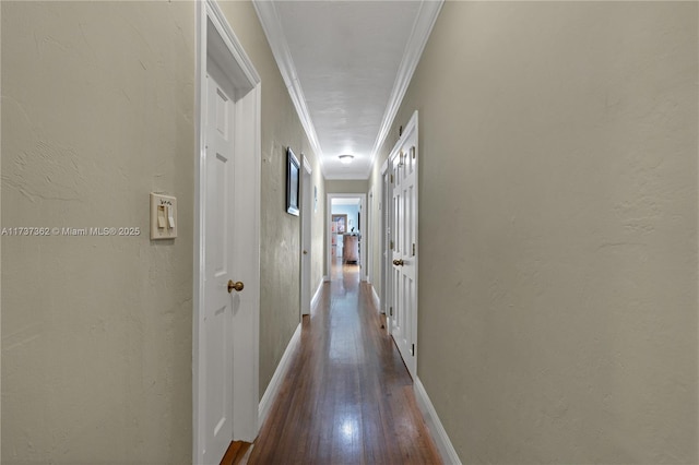 corridor with ornamental molding and hardwood / wood-style floors