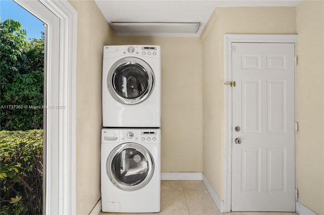 washroom with stacked washer and dryer and light tile patterned floors