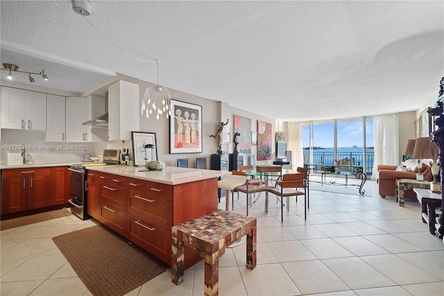 kitchen with decorative light fixtures, stainless steel electric range, light tile patterned floors, a wall of windows, and white cabinets