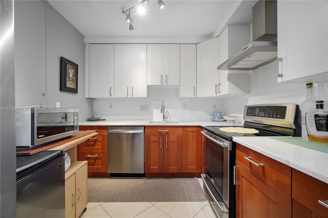 kitchen featuring white cabinetry, appliances with stainless steel finishes, sink, and wall chimney range hood