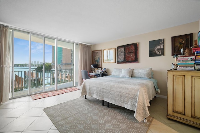 tiled bedroom featuring a water view, access to exterior, and a wall of windows