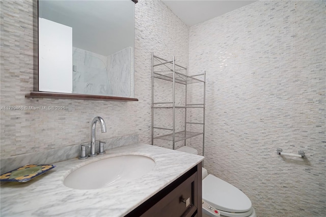 bathroom with vanity, tile walls, and toilet