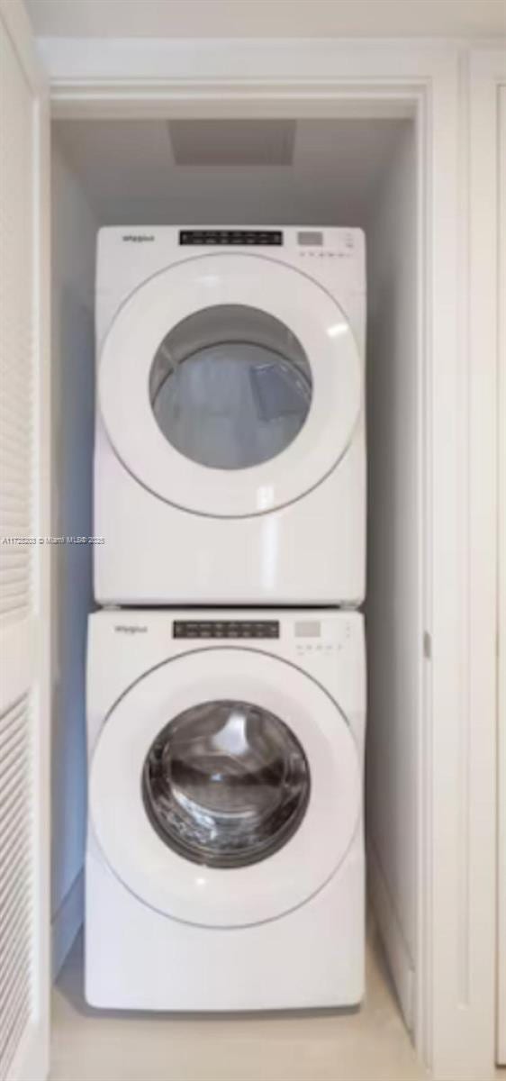 clothes washing area with stacked washer and clothes dryer