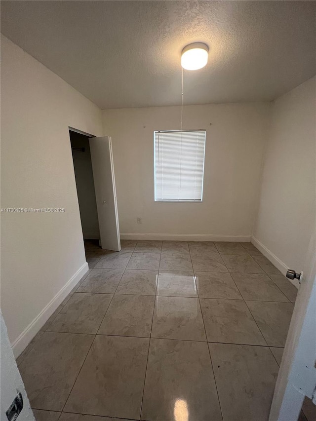 spare room featuring light tile patterned floors and a textured ceiling