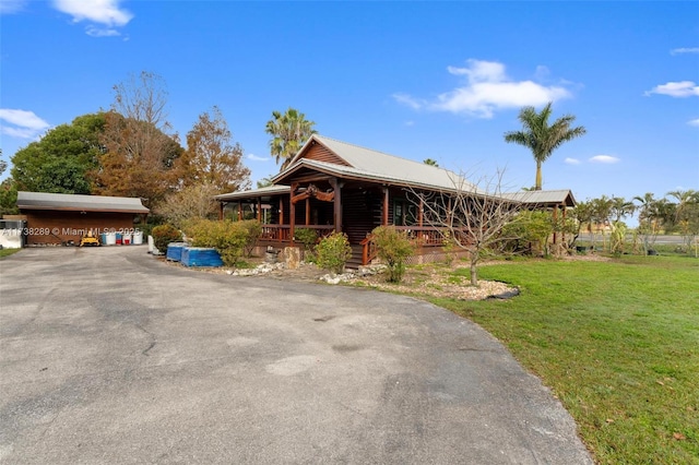 view of front of house with a carport, covered porch, and a front lawn