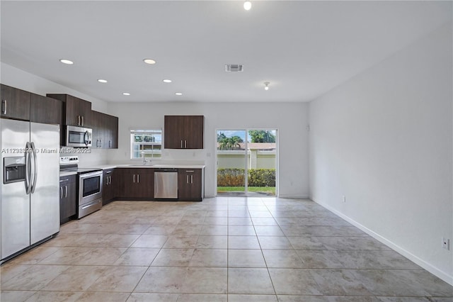 kitchen featuring a healthy amount of sunlight, appliances with stainless steel finishes, dark brown cabinets, and light tile patterned floors