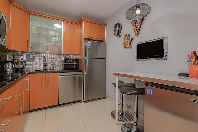 kitchen with light tile patterned flooring, appliances with stainless steel finishes, sink, and backsplash