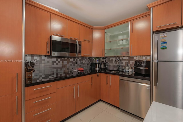 kitchen with sink, light tile patterned floors, appliances with stainless steel finishes, dark stone countertops, and tasteful backsplash