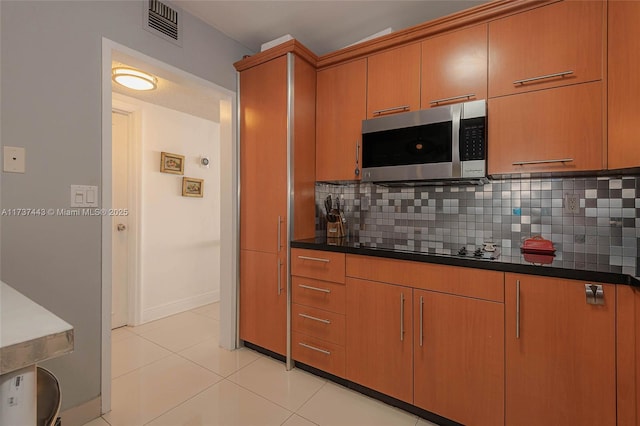 kitchen featuring light tile patterned floors, decorative backsplash, and black electric stovetop