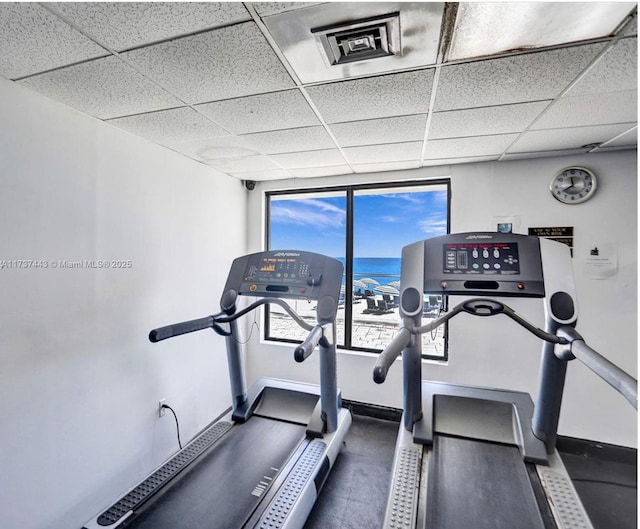 exercise room with a paneled ceiling and a water view