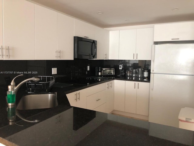 kitchen featuring black appliances, tasteful backsplash, white cabinets, and a sink