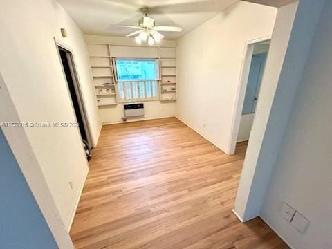 spare room with built in shelves, light hardwood / wood-style flooring, and ceiling fan