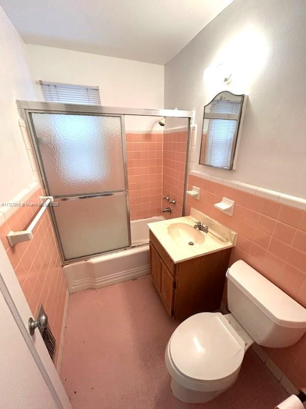 full bathroom with vanity, tile walls, shower / bath combination with glass door, and toilet