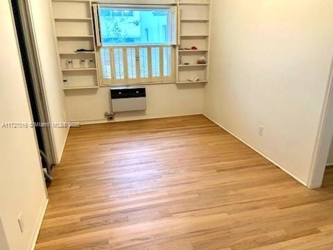 unfurnished room with heating unit and light hardwood / wood-style floors