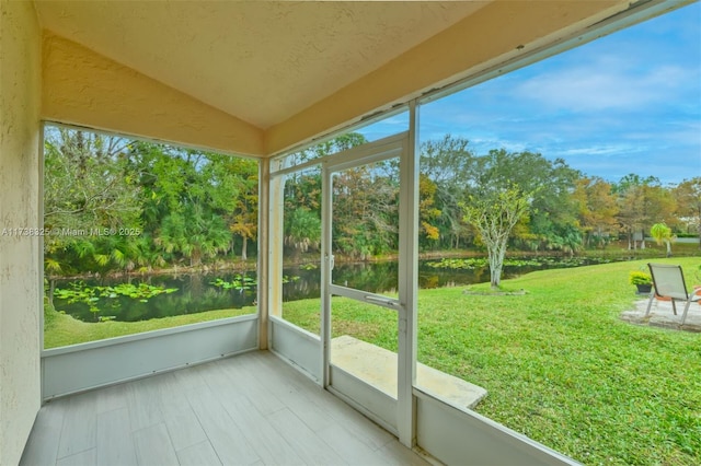 unfurnished sunroom featuring lofted ceiling, a healthy amount of sunlight, and a water view