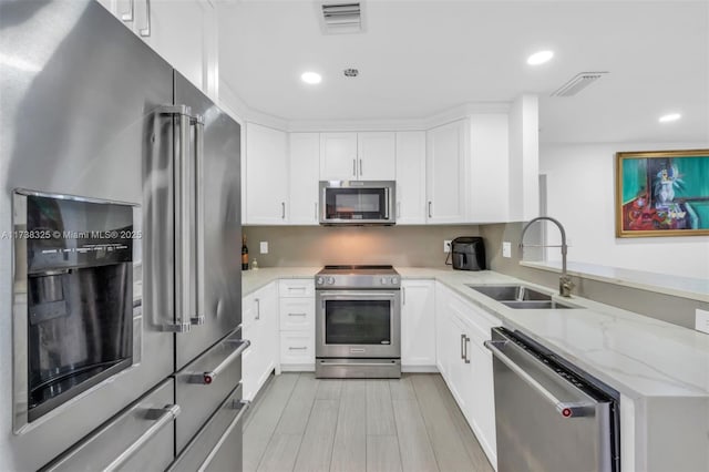 kitchen featuring white cabinetry, appliances with stainless steel finishes, sink, and light stone counters