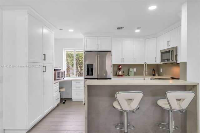 kitchen featuring appliances with stainless steel finishes, white cabinetry, sink, a kitchen breakfast bar, and light hardwood / wood-style flooring