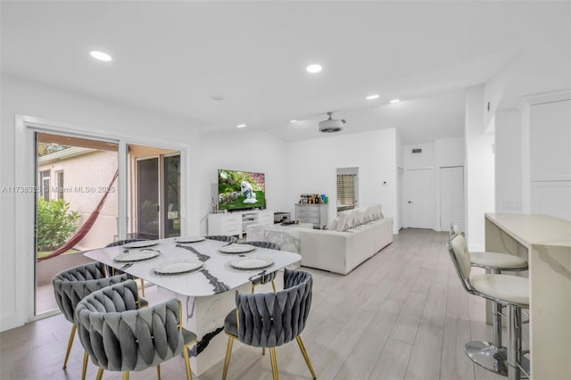 dining room with vaulted ceiling and light hardwood / wood-style floors