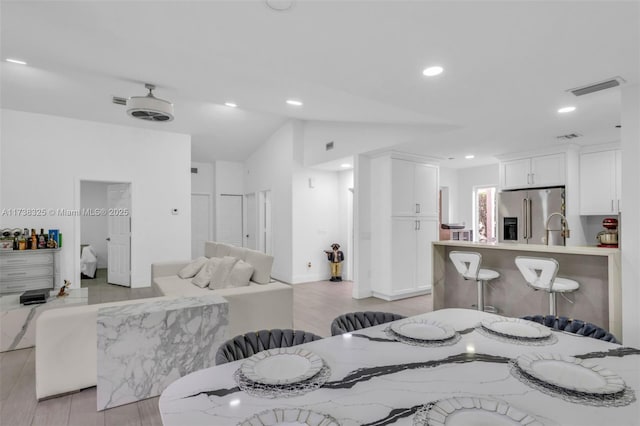 dining space with lofted ceiling and light hardwood / wood-style floors