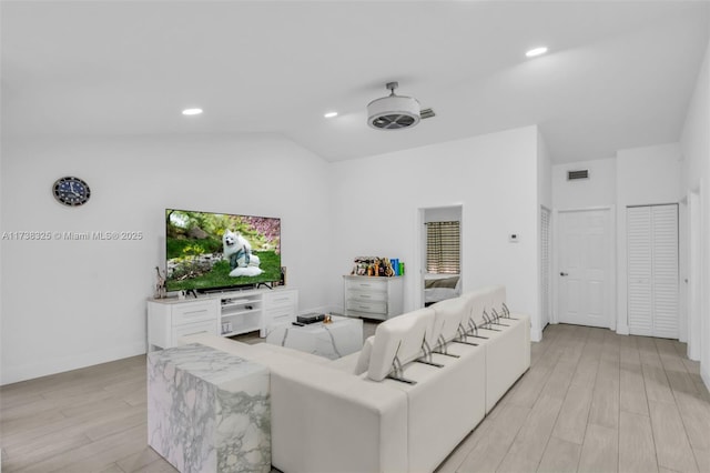 living room featuring ceiling fan, lofted ceiling, and light hardwood / wood-style flooring