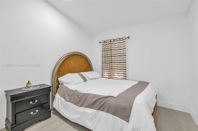 bedroom featuring vaulted ceiling and light wood-type flooring