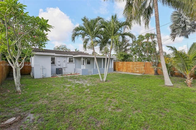 back of house with a yard and central AC