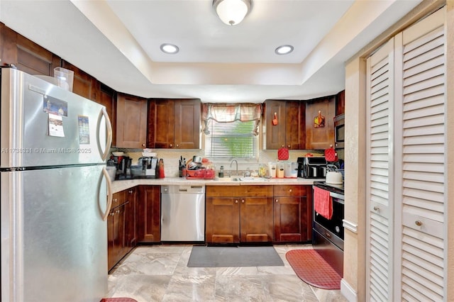 kitchen with sink, decorative backsplash, a raised ceiling, and appliances with stainless steel finishes