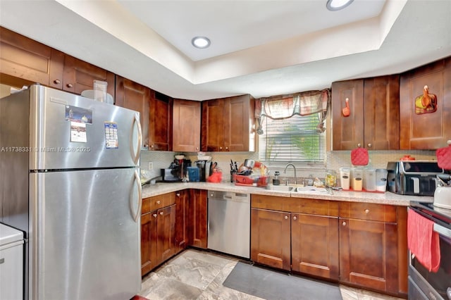 kitchen with tasteful backsplash, stainless steel appliances, a raised ceiling, and sink