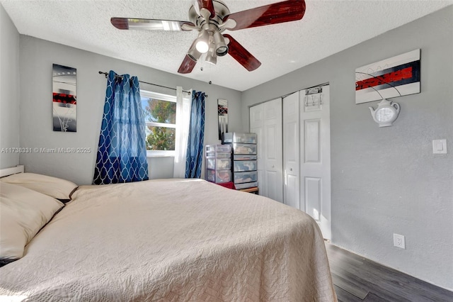 bedroom with a closet, dark hardwood / wood-style floors, a textured ceiling, and ceiling fan