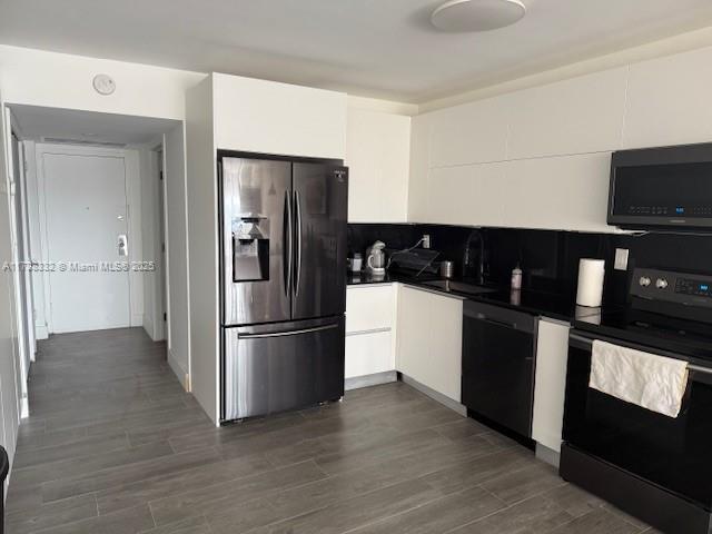 kitchen featuring white cabinetry, sink, black appliances, and dark hardwood / wood-style floors