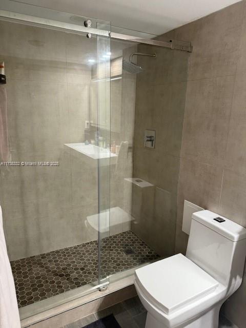 bathroom featuring tile walls, an enclosed shower, and toilet