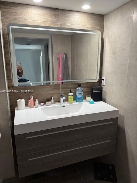 bathroom with tasteful backsplash, vanity, and tile walls