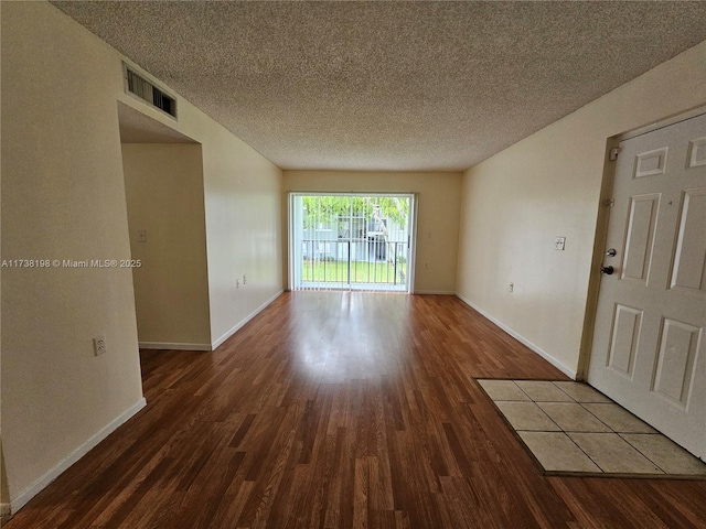 unfurnished room featuring dark wood-type flooring and a textured ceiling