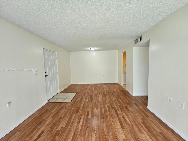 empty room featuring a textured ceiling and light hardwood / wood-style floors