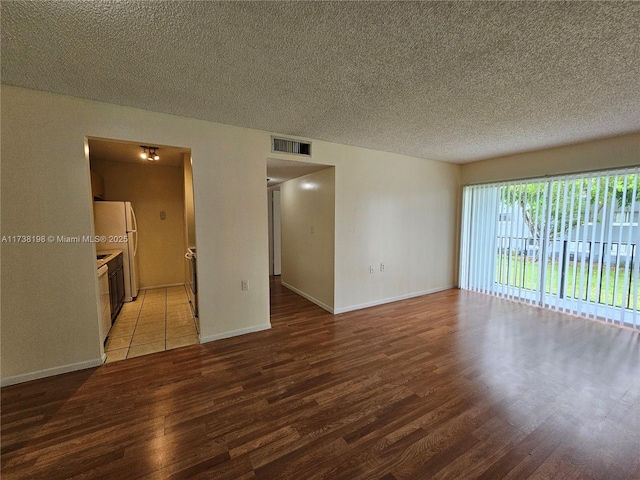 unfurnished room with hardwood / wood-style floors and a textured ceiling