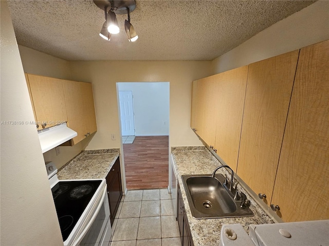 kitchen featuring sink, white electric range oven, light tile patterned floors, light brown cabinets, and a textured ceiling