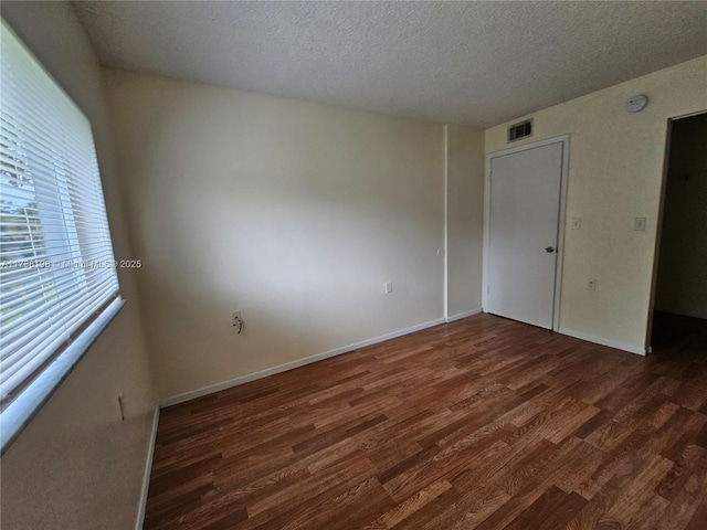 empty room featuring dark hardwood / wood-style flooring and a textured ceiling