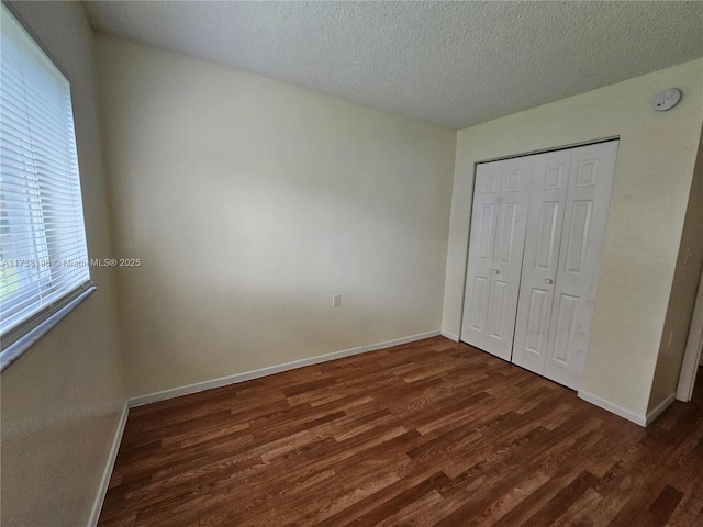 unfurnished bedroom featuring dark wood-type flooring, a closet, and a textured ceiling