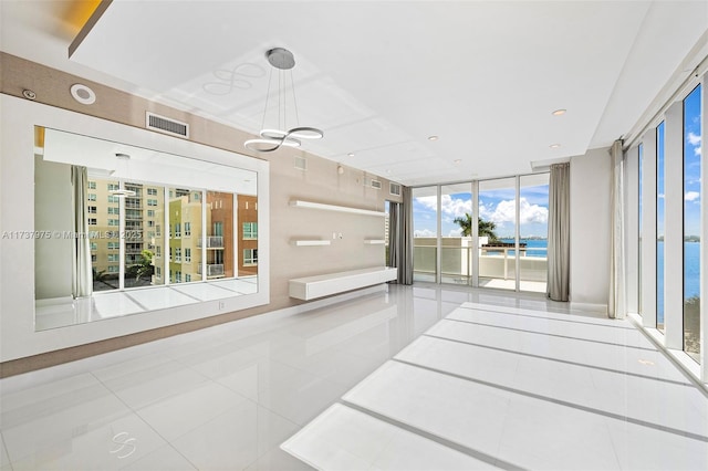 unfurnished room featuring light tile patterned flooring, a water view, floor to ceiling windows, and an inviting chandelier