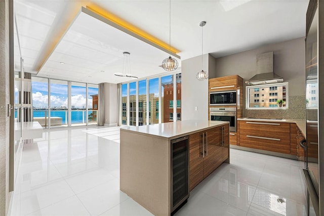 kitchen with tasteful backsplash, wine cooler, a large island, a water view, and wall chimney exhaust hood